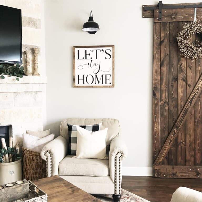 Barn door and off-white studded armchair in farmhouse living room with walls in Sherwin-William Agreeable Gray