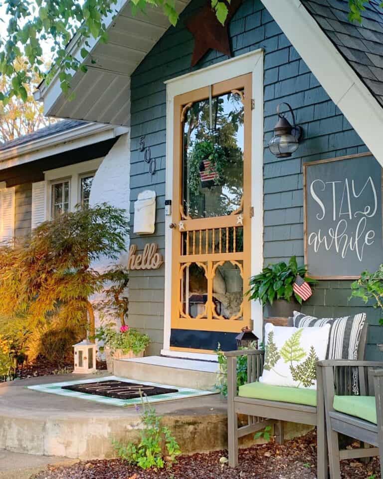 A Black Outdoor Farmhouse Light Fixture Above Two Grey Chairs